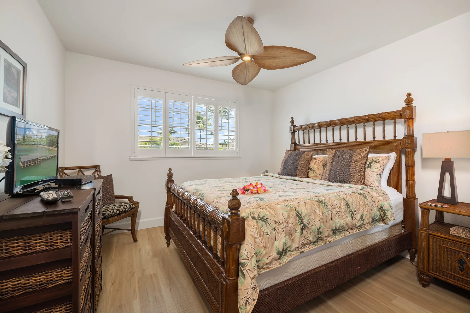 A bedroom with a wooden bed, light bedding, and a window with shutters.