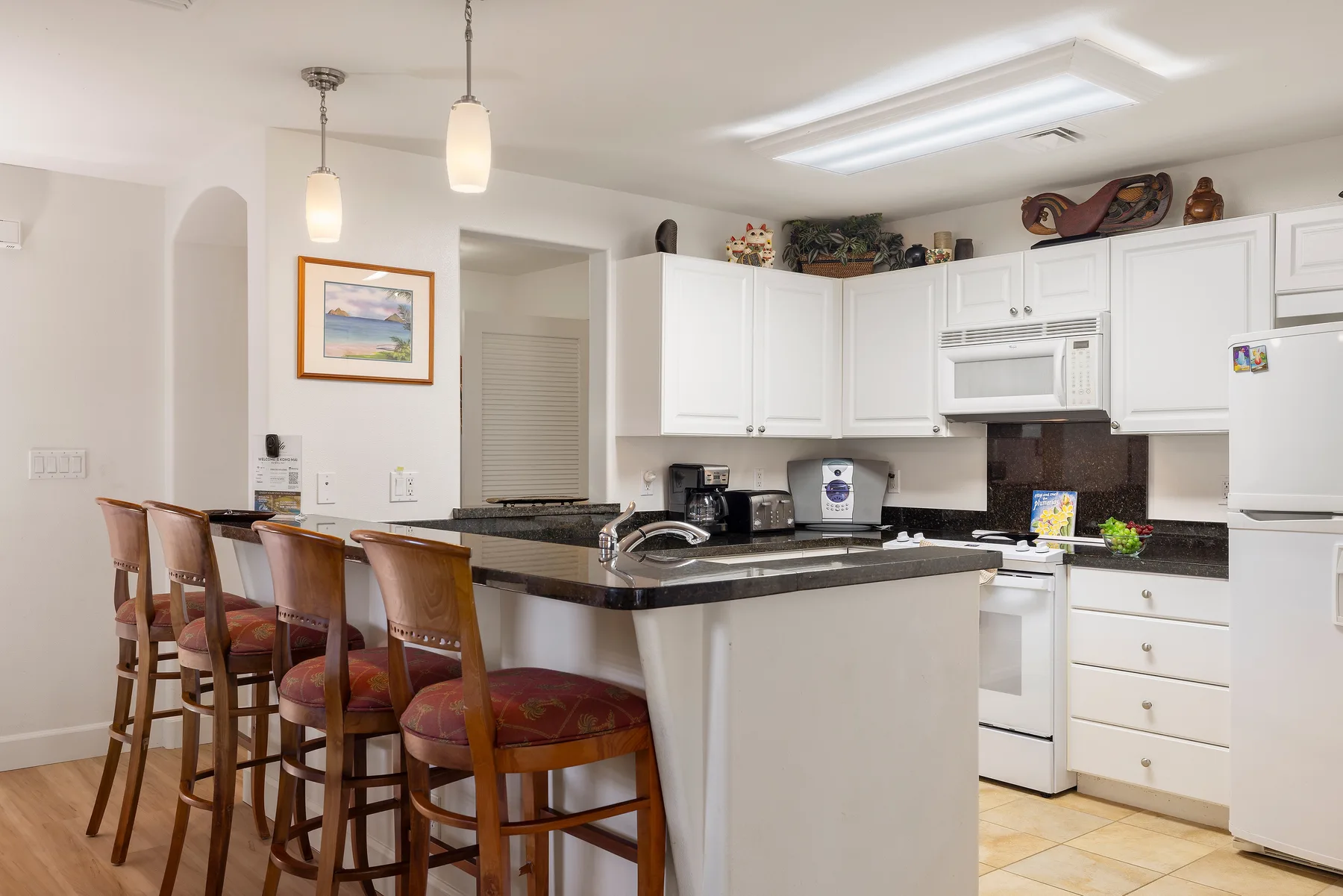 Una cocina luminosa con una isla central y asientos junto a la barra.