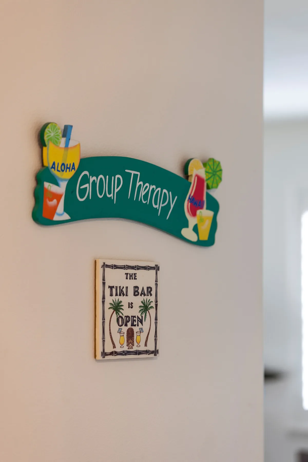 A wall displays a colorful “Group Therapy” sign above a “Tiki Bar” sign.