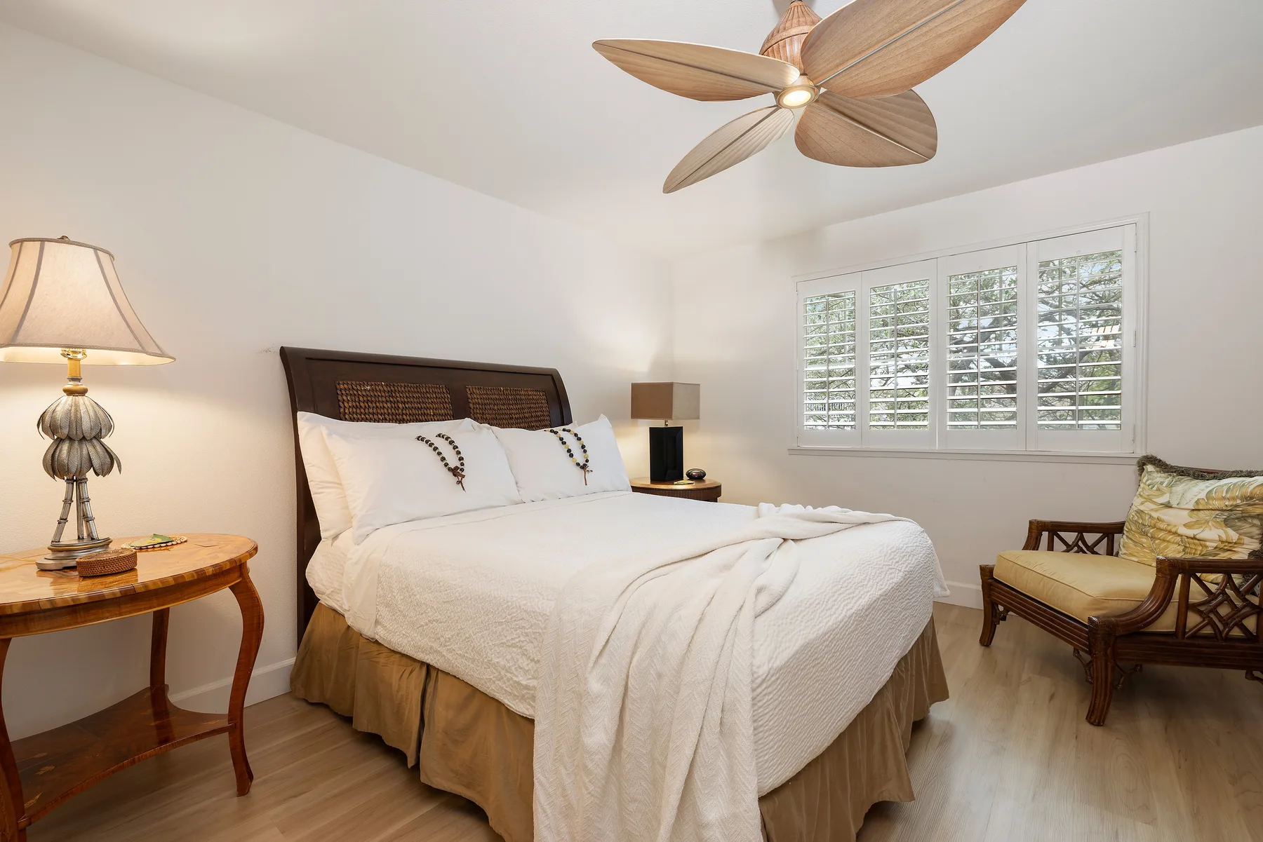 A bright bedroom with a neatly made bed and a window with shutters.