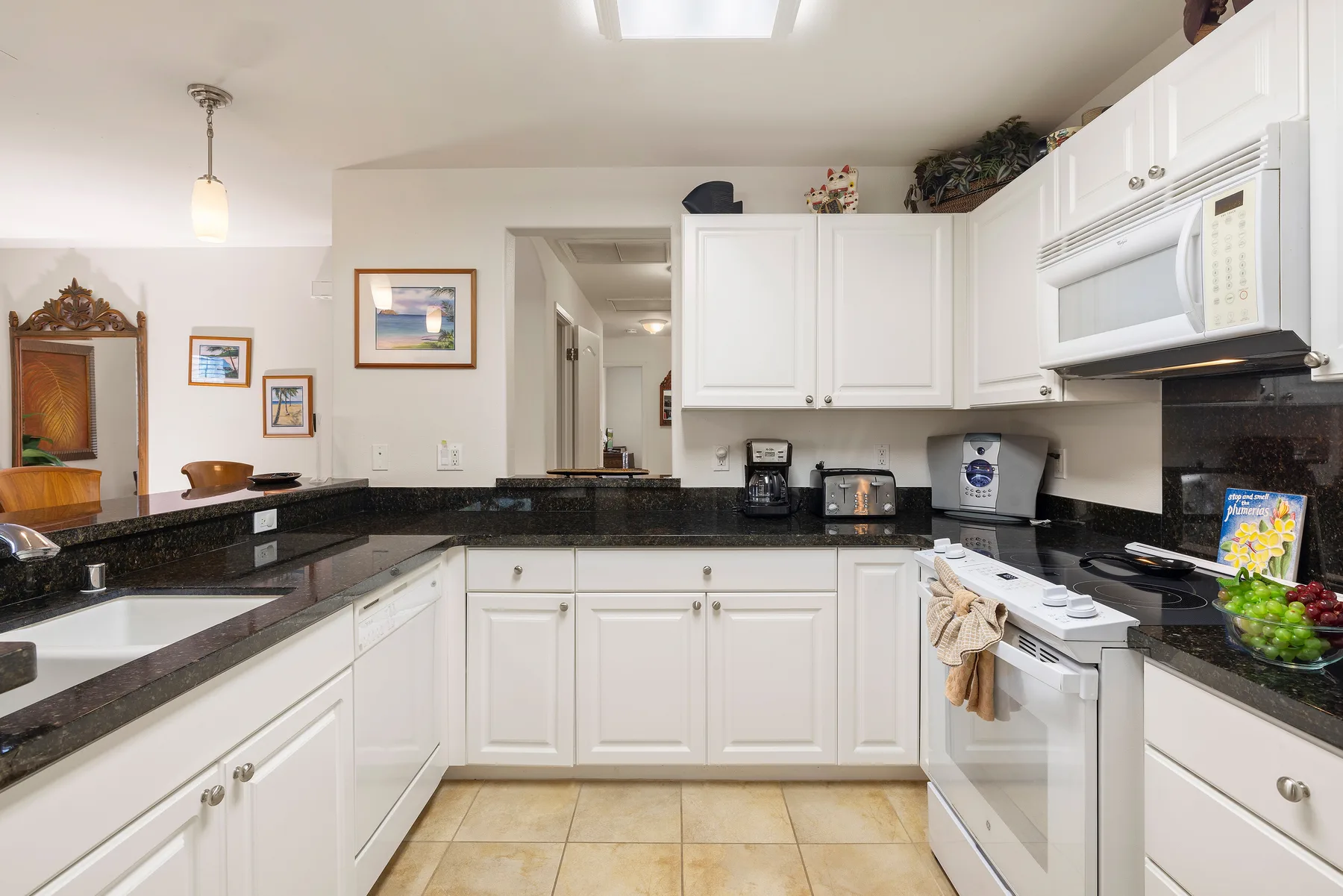 A kitchen with white cabinets, dark countertops, and cooking appliances.