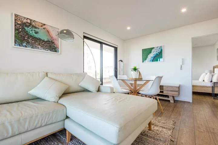 Sala de estar con asientos claros y un comedor junto a las ventanas.