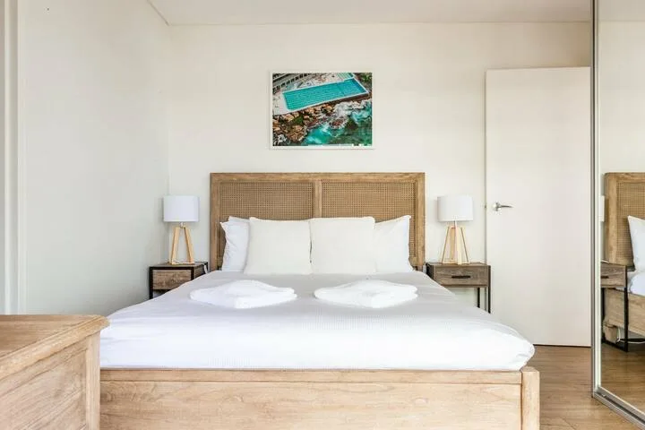 Un dormitorio con una cama doble, mesitas de noche y un cuadro en la pared.