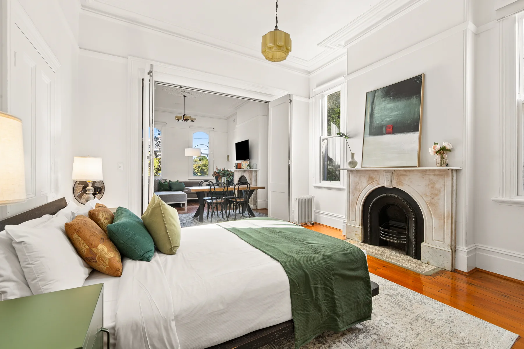 Un dormitorio con una cama frente a un comedor abierto y una chimenea.