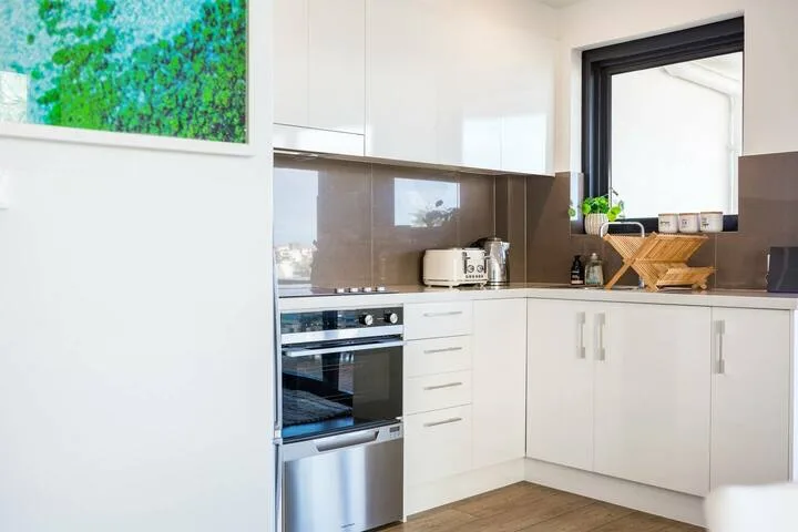 Una cocina luminosa con gabinetes blancos, un horno empotrado y una ventana.