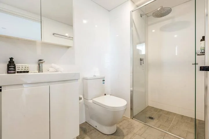 Un baño moderno con lavabo, inodoro y ducha de vidrio.