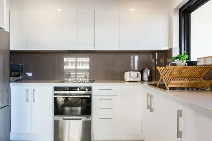 Una cocina moderna con gabinetes blancos, un horno y un escurridor de platos.