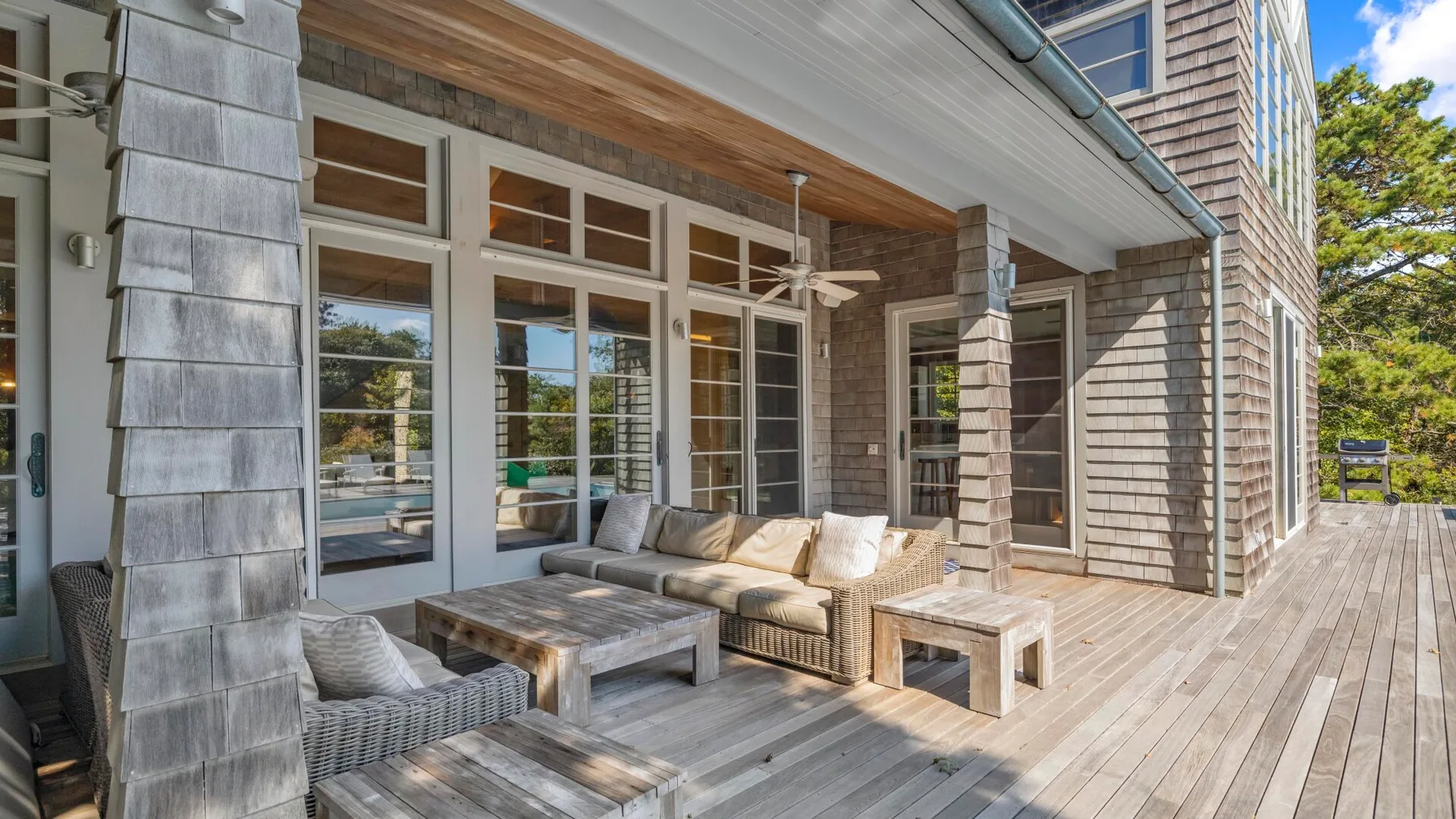 Una terraza exterior con asientos y grandes puertas de vidrio junto a la casa.