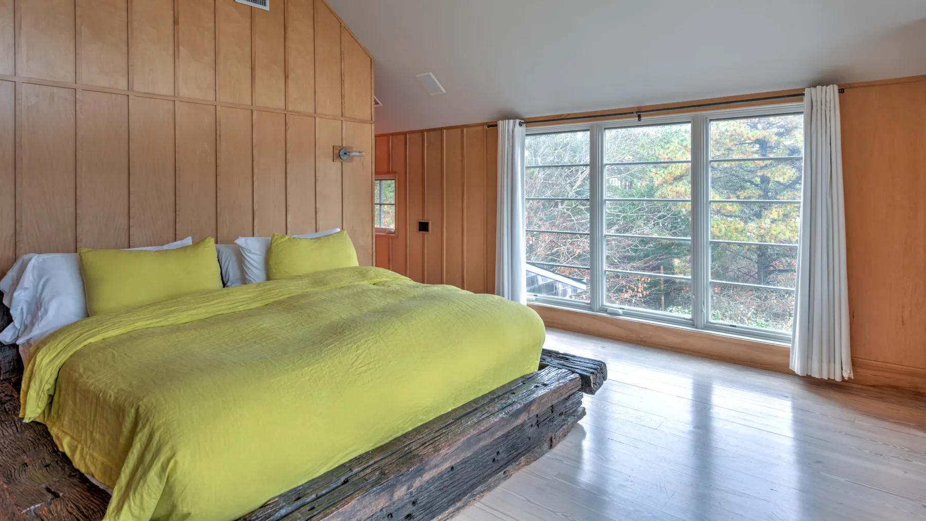 Un dormitorio con una cama cubierta con una colcha verde brillante junto a una ventana grande.