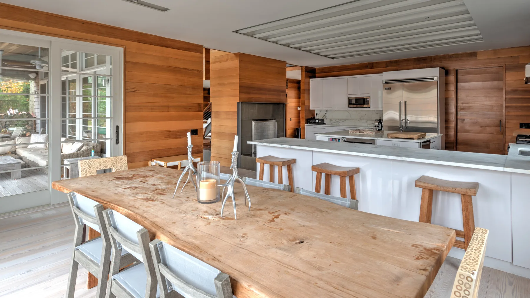 Una cocina y comedor con paredes de madera, una mesa larga y una isla.
