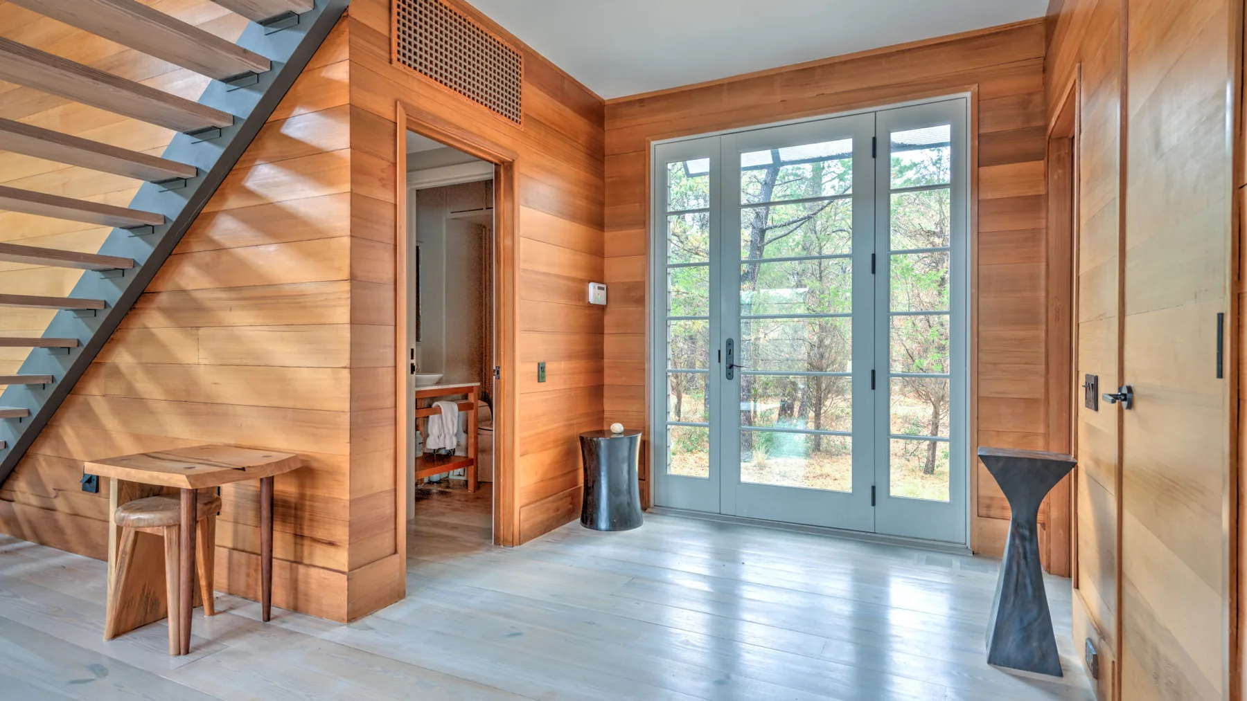 Un recibidor revestido de madera con puertas de vidrio grandes y una escalera.