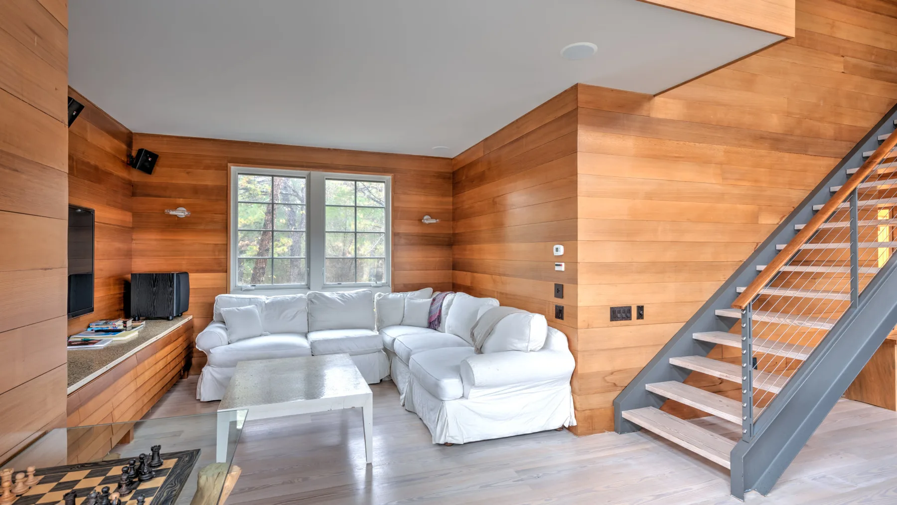 Una sala revestida de madera con una zona de asientos y una escalera.