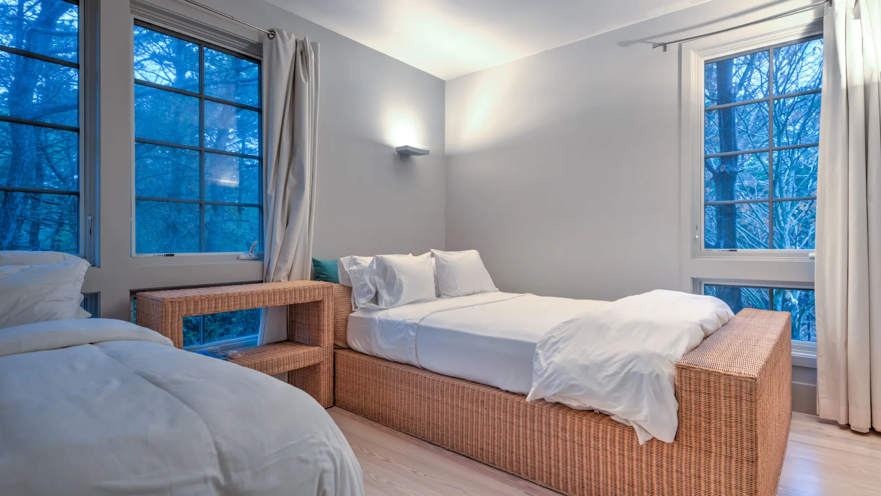 Un dormitorio con dos camas y ventanas grandes.