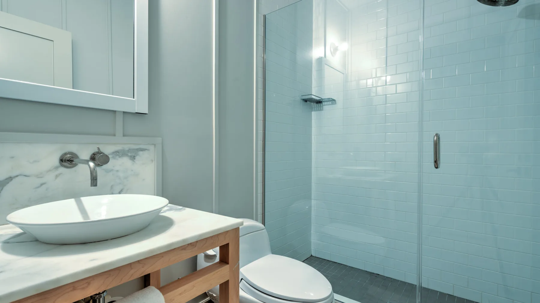 Un baño con lavabo, inodoro y ducha con mampara de vidrio.