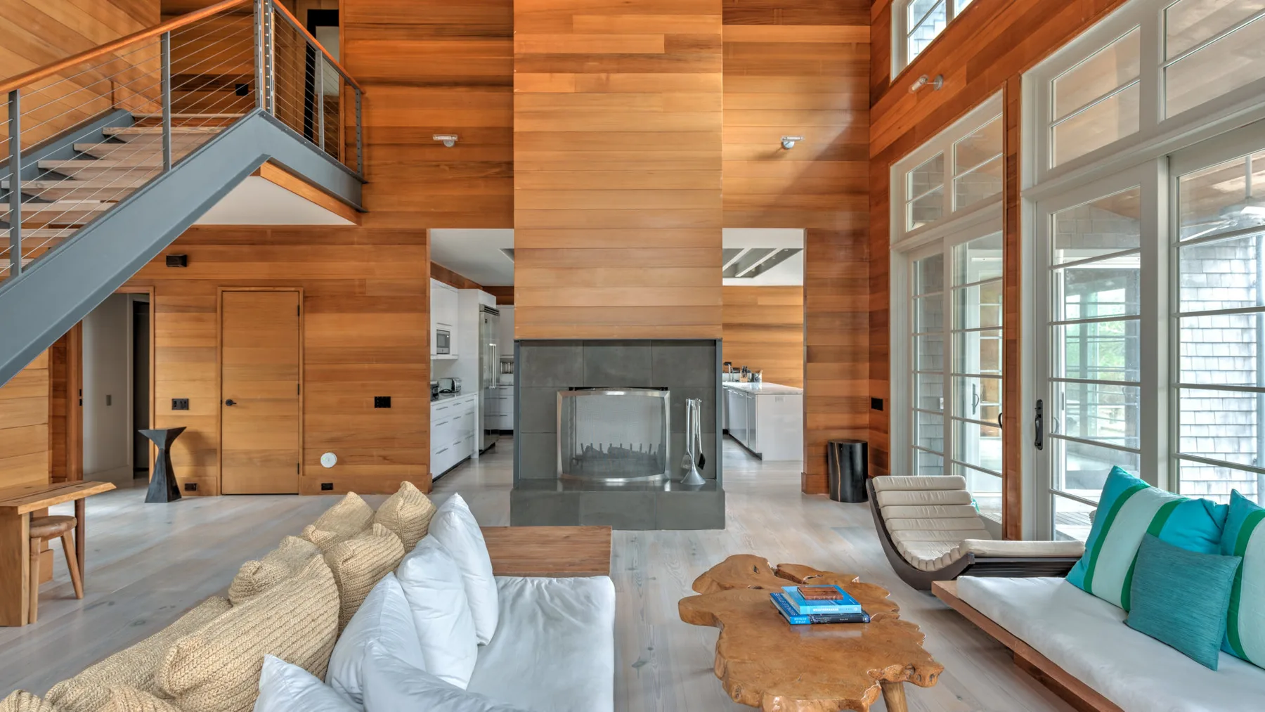 Una sala de estar revestida de madera con asientos, chimenea y ventanas altas.