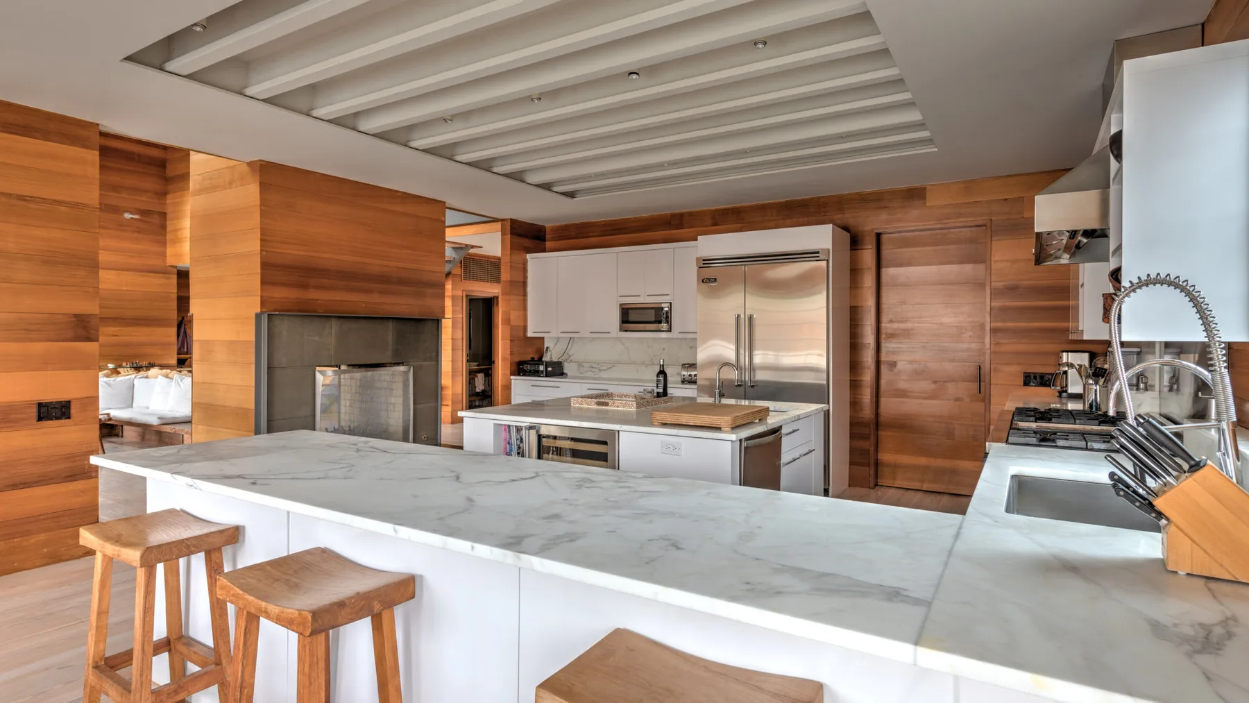 Una cocina moderna con una gran isla, electrodomésticos de acero inoxidable y paredes revestidas de madera.