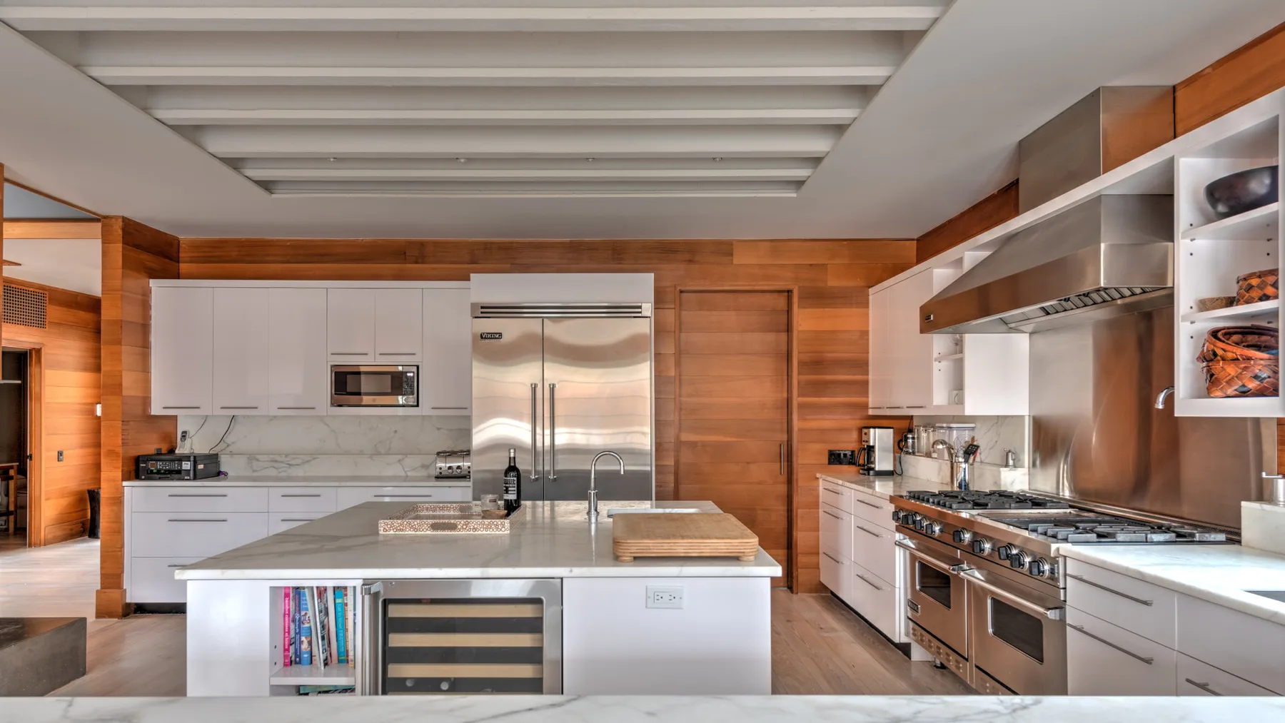 Una cocina amplia con gabinetes blancos, una isla central y electrodomésticos de acero inoxidable.