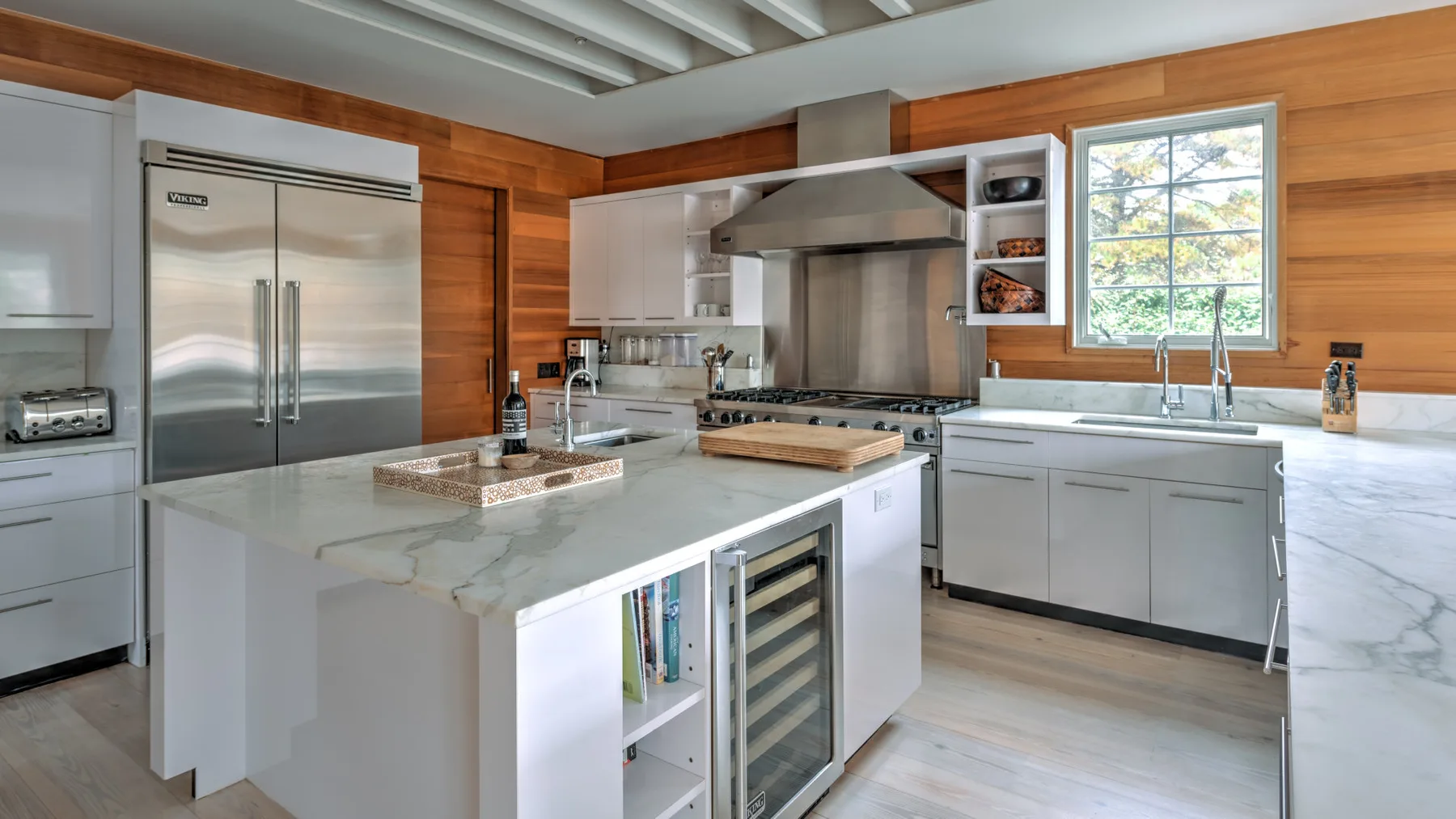 Una cocina moderna con gabinetes blancos, electrodomésticos de acero inoxidable y una isla grande.
