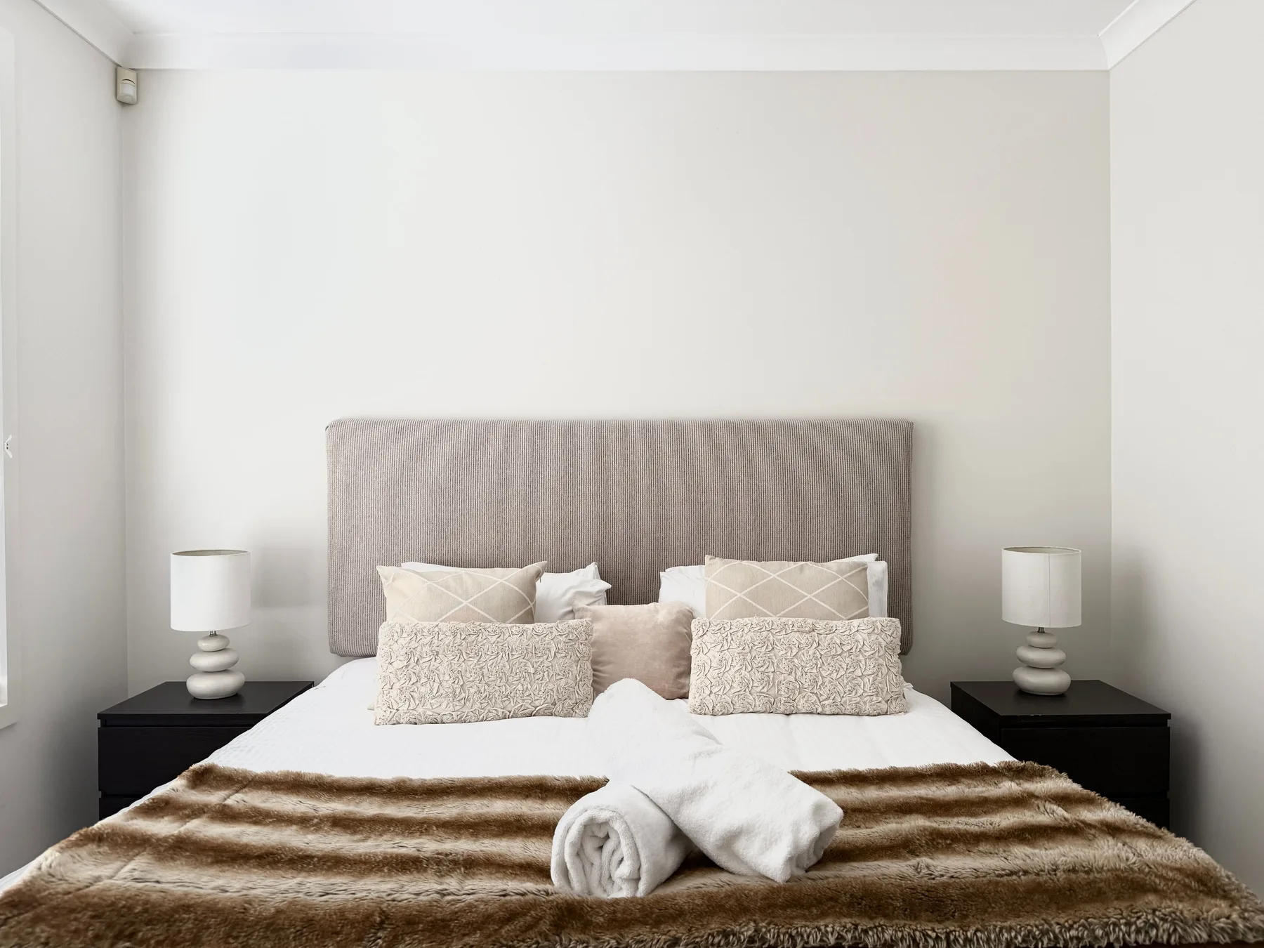 A bedroom with a neatly made bed and matching bedside tables.