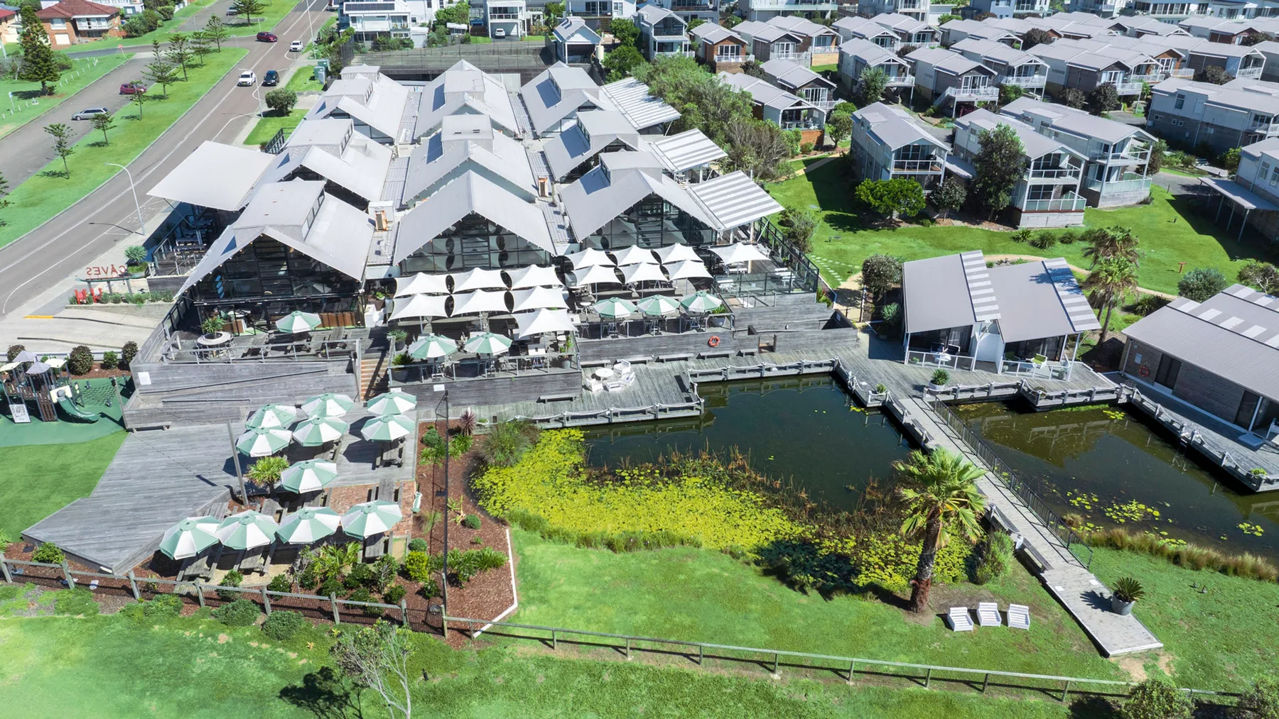 An aerial view shows a waterfront venue with outdoor seating and nearby buildings.