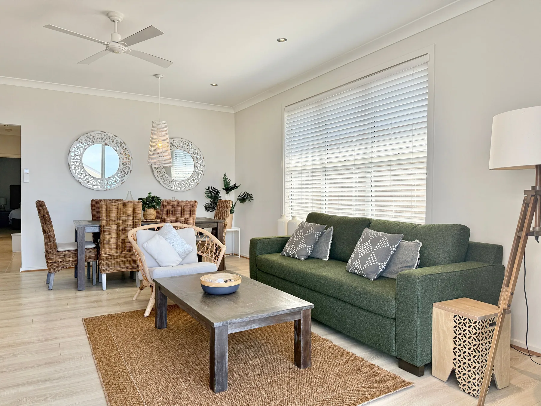 A bright living room with green seating and a dining area.