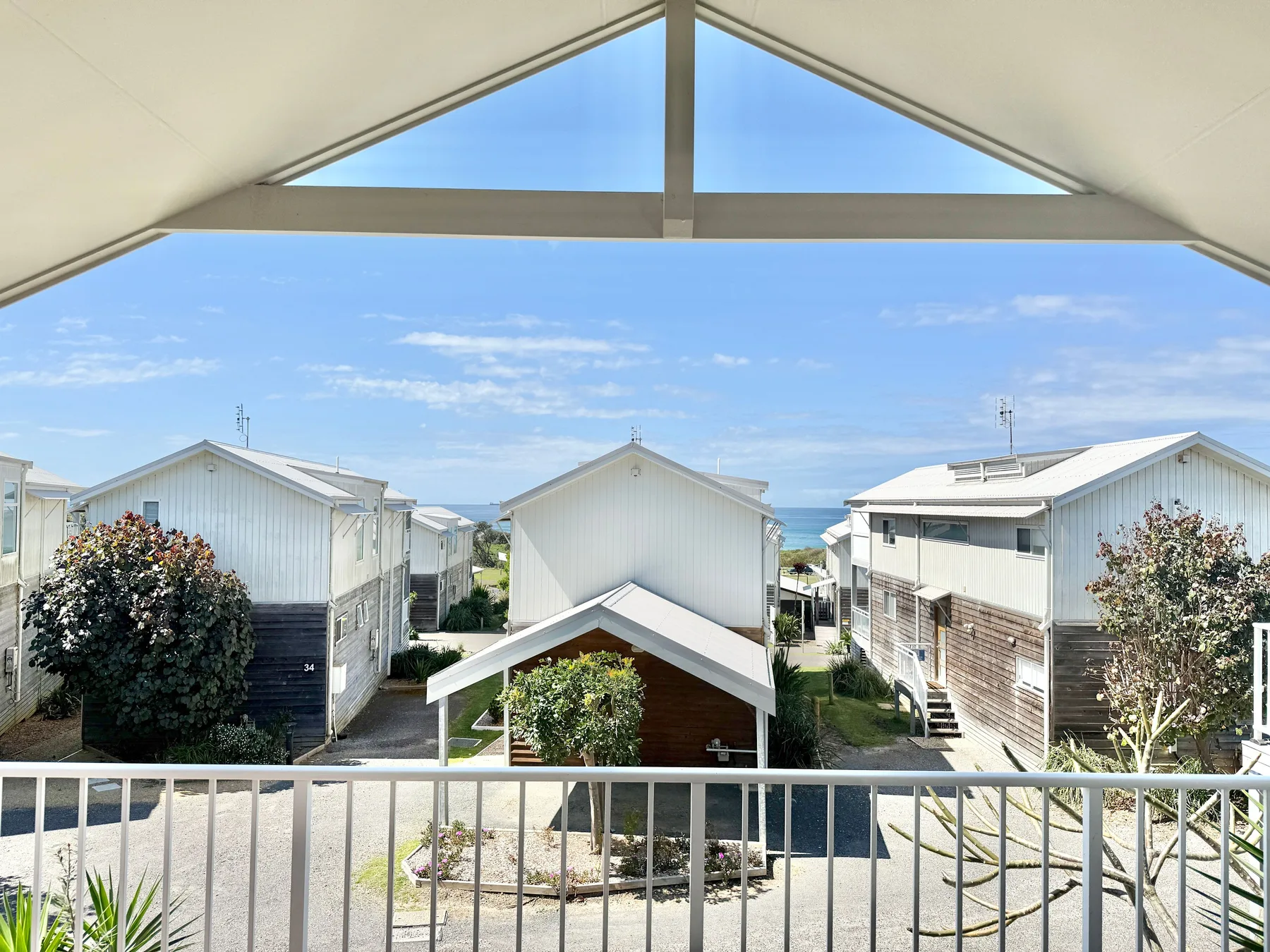 A balcony overlooks several buildings beneath a bright blue sky.