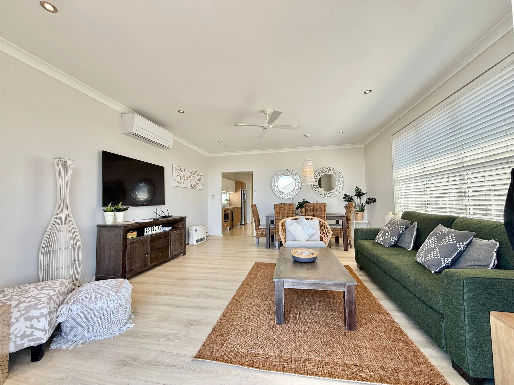 A bright living room with seating arranged around a coffee table and television.