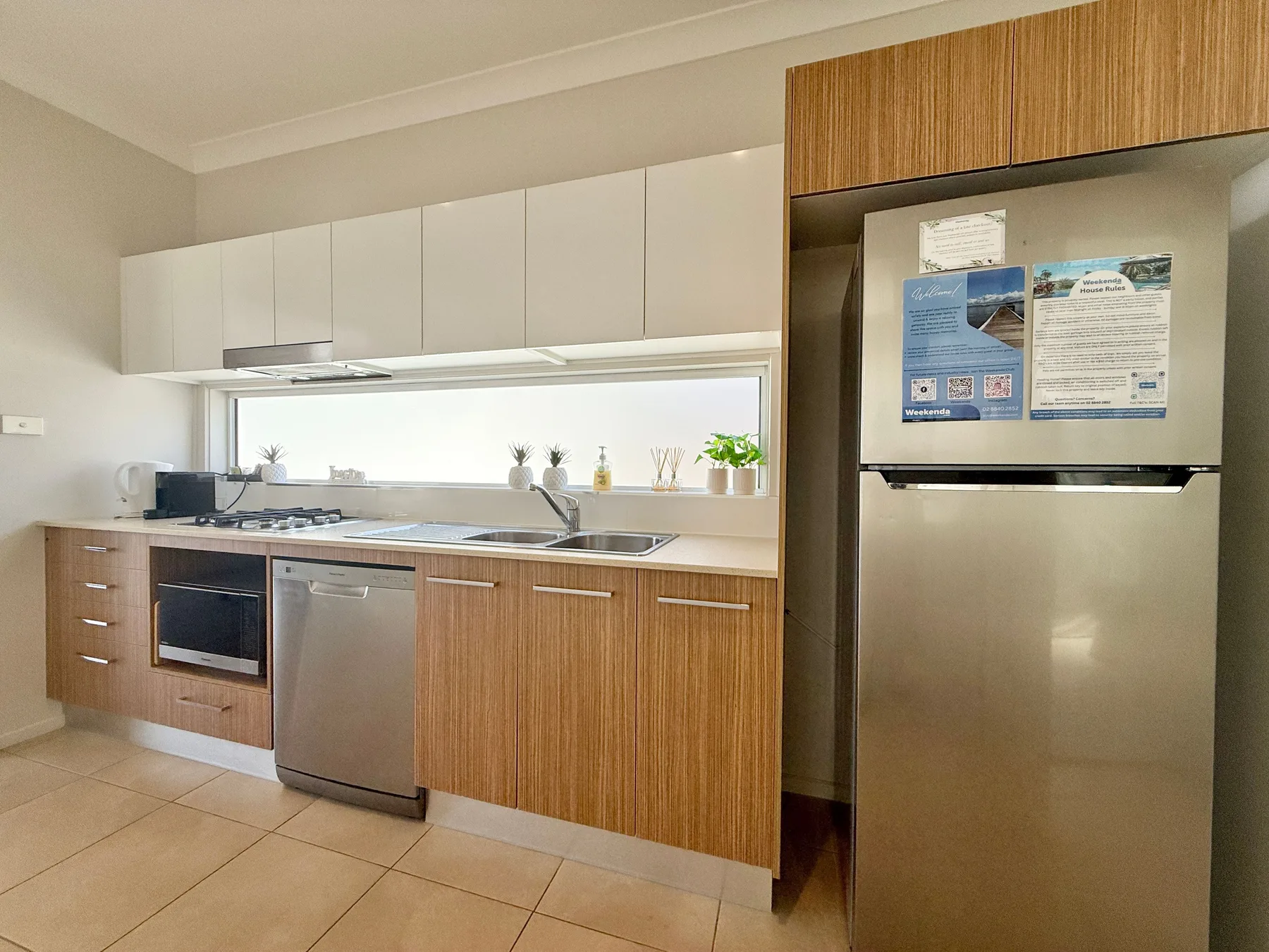A modern kitchen with wood-front cabinets, a sink, and stainless-steel appliances.