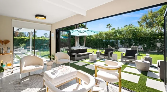 Una sala luminosa da a un patio con asientos al aire libre y un jardín.