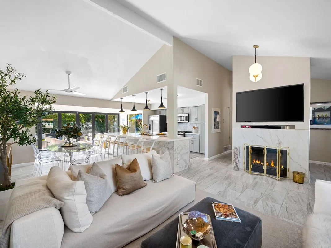 Sala de estar de concepto abierto con asientos, chimenea e isla de cocina.