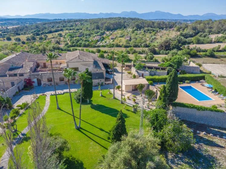 A rural property sits beside a green lawn and a rectangular swimming pool.