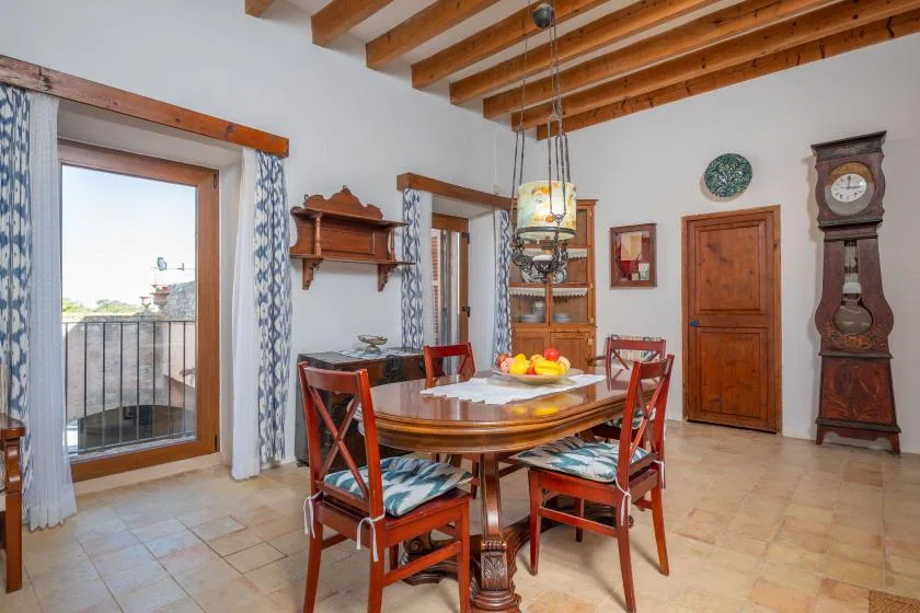 A dining room with a wooden table and exposed ceiling beams.