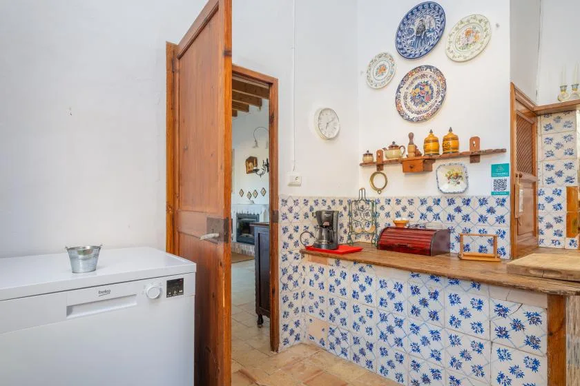 A tiled kitchen with a washing machine and wooden counter.