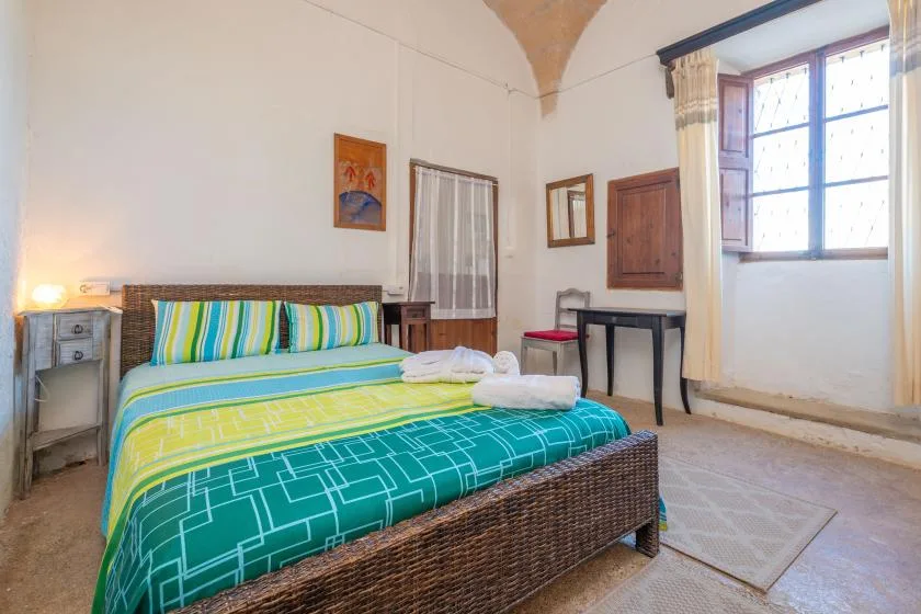 A bedroom with a bed dressed in colorful striped bedding and a large window.