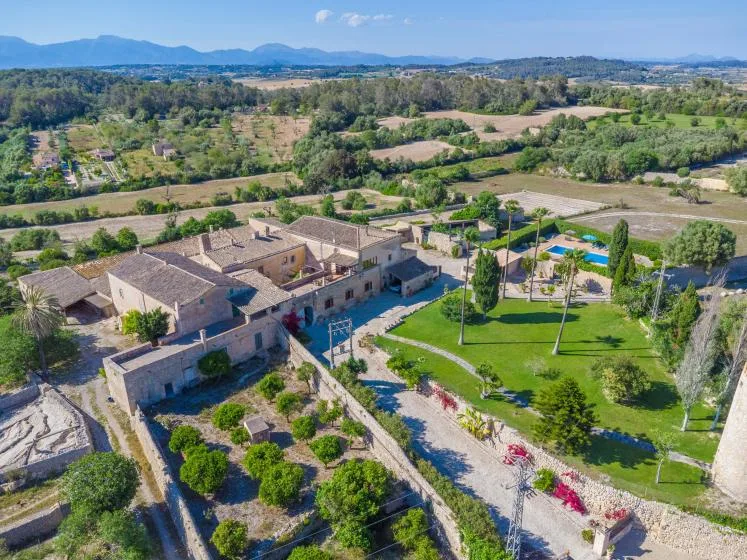 Aerial view of a rural property with stone buildings, landscaped grounds, and surrounding fields.