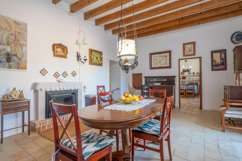 A dining room with a long wooden table, chairs, and a fireplace.