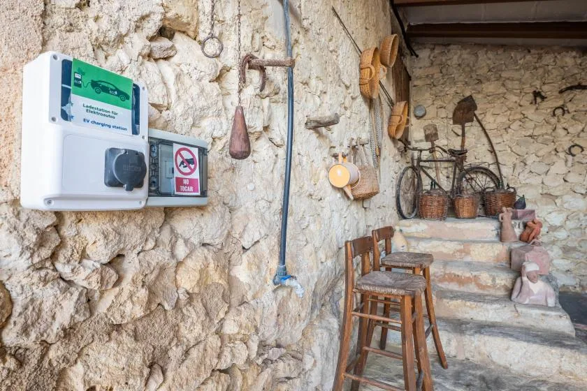A rustic stone interior with a wooden chair and old tools displayed on the walls.