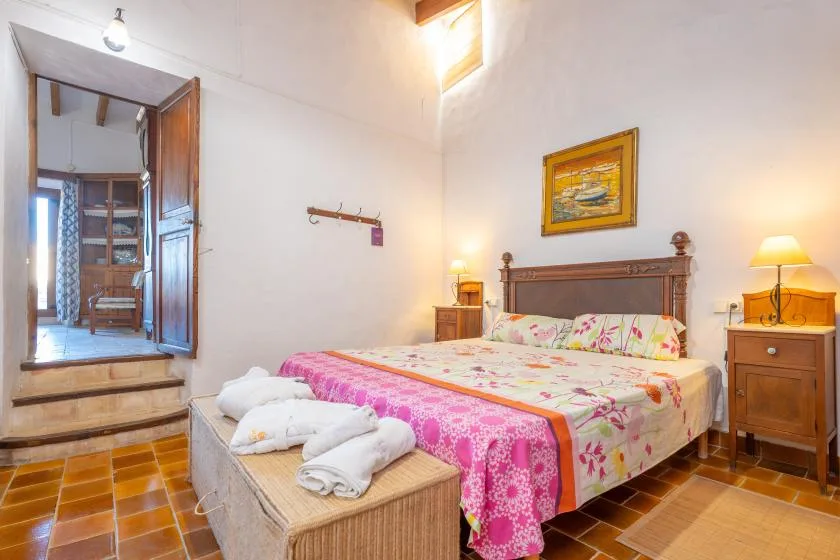 A bedroom with a wooden bed, colorful floral bedding, and bedside tables.