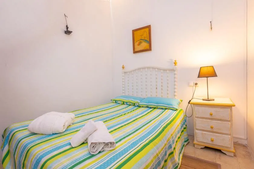 A bedroom with a striped bedspread and a bedside table with a lamp.