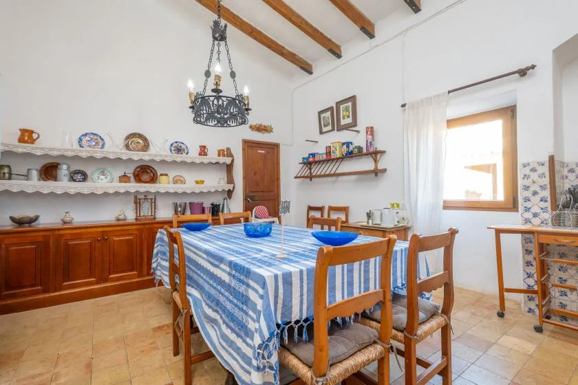 A dining room with a blue-and-white checked tablecloth and wooden chairs.