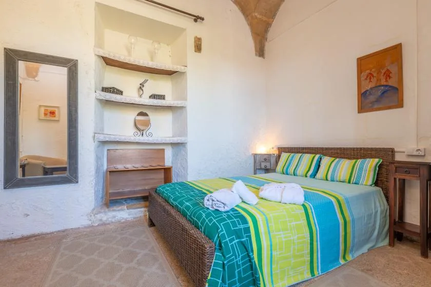 A bedroom with a bed dressed in bright blue, green, and white bedding.