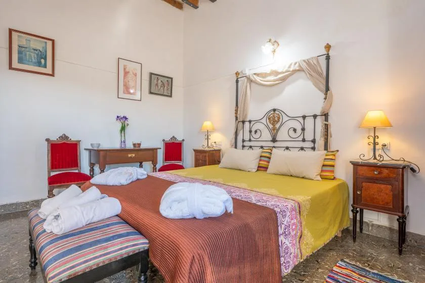 A bedroom with two beds, a decorative metal headboard, and bedside lamps.