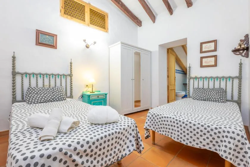A bedroom with two beds, patterned bedding, and a white wardrobe.