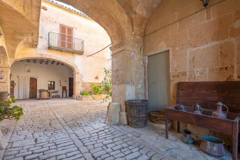 A stone courtyard with an arched passage and a wooden water trough.
