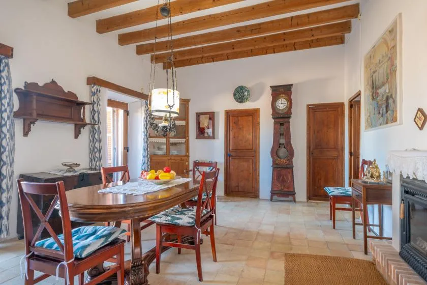 A dining room with a wooden table and chairs beneath exposed ceiling beams.