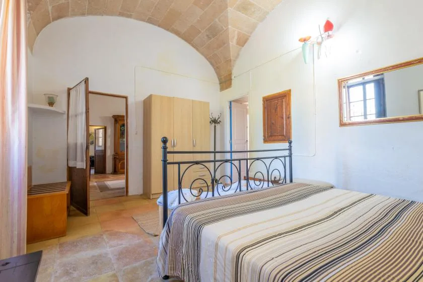 A bedroom with a bed beneath a vaulted stone ceiling.