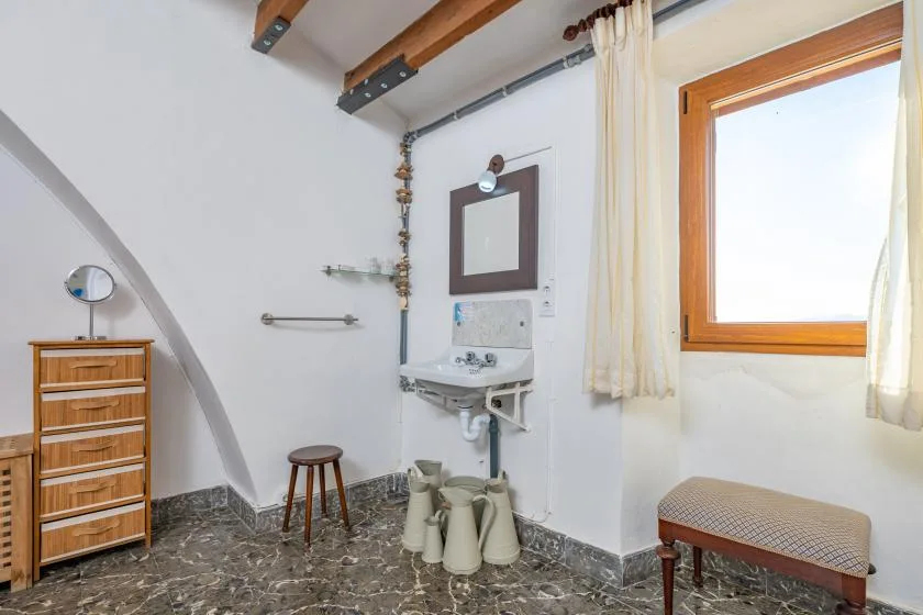 A bathroom with a wall-mounted sink and a window.