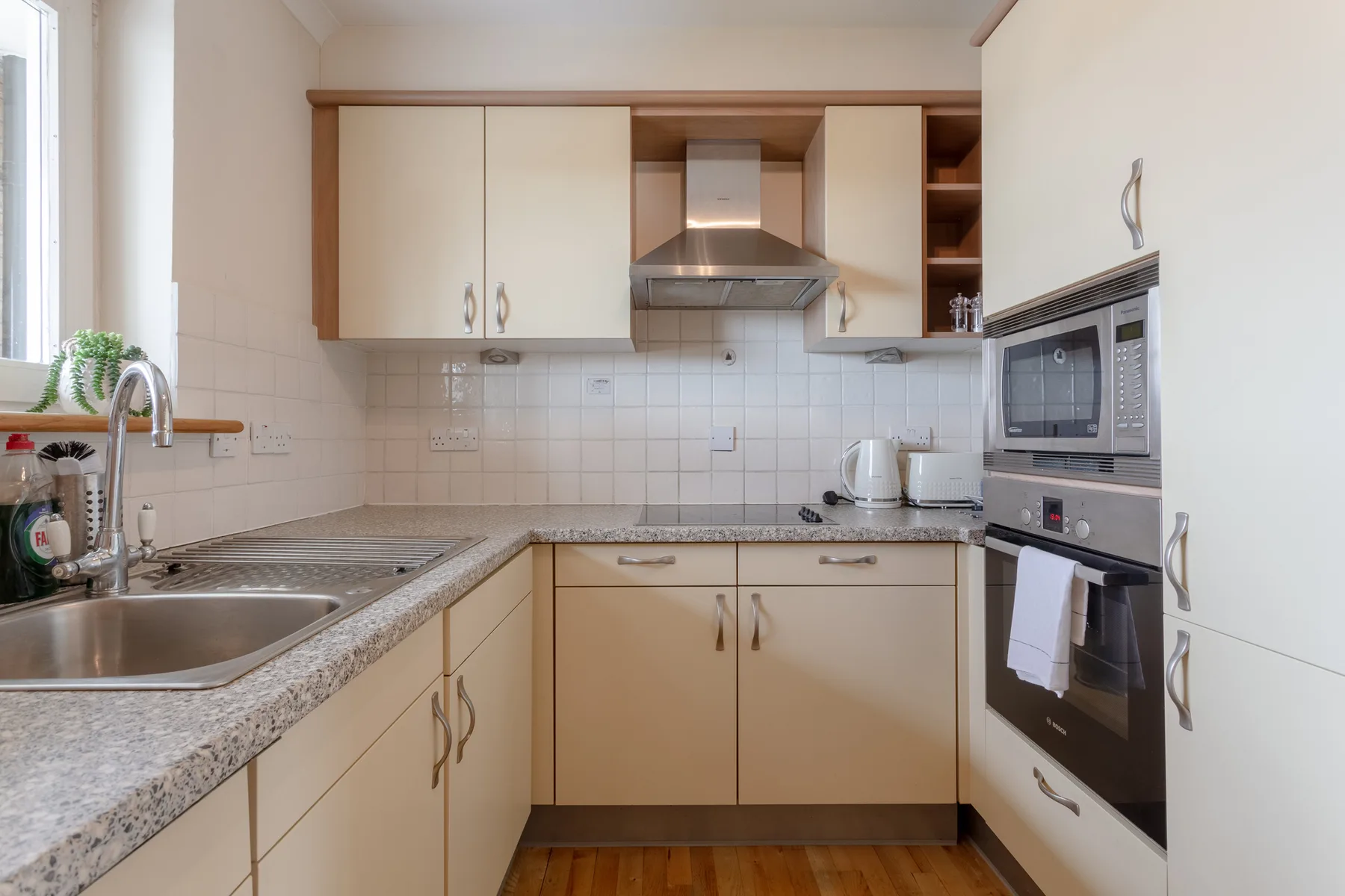 A bright kitchen with light cabinets, a countertop, and built-in appliances.