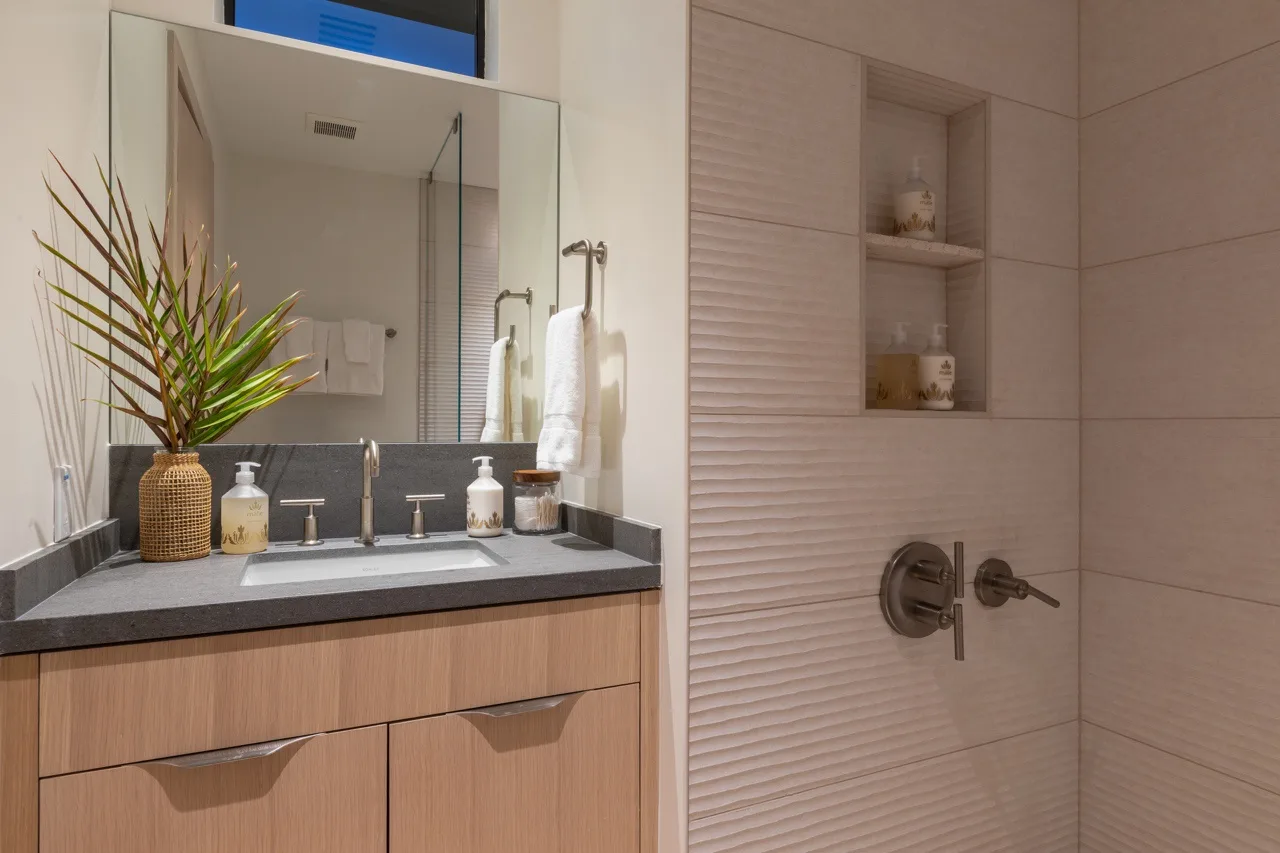 A bathroom vanity with a sink sits beside a tiled shower area.