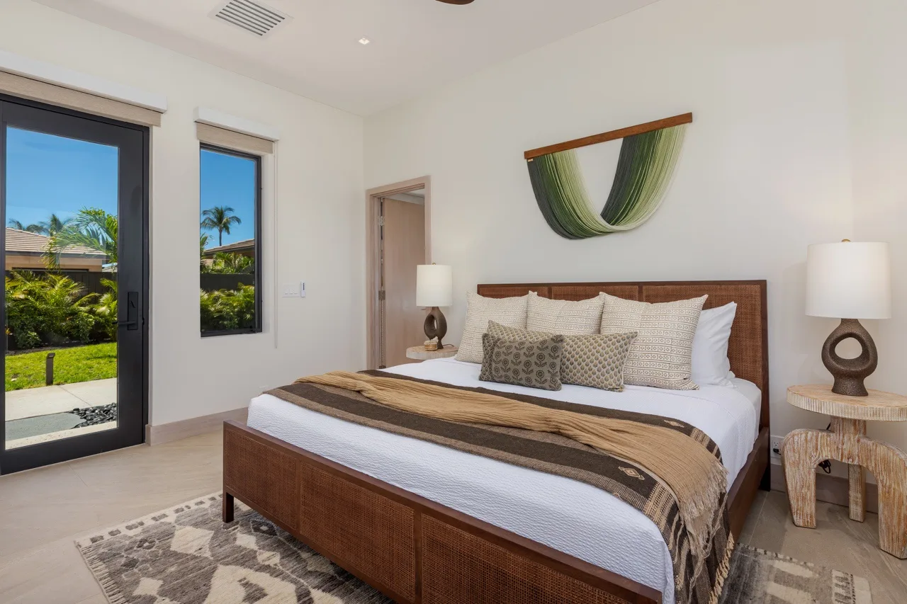 A bright bedroom with a large bed and windows overlooking greenery.